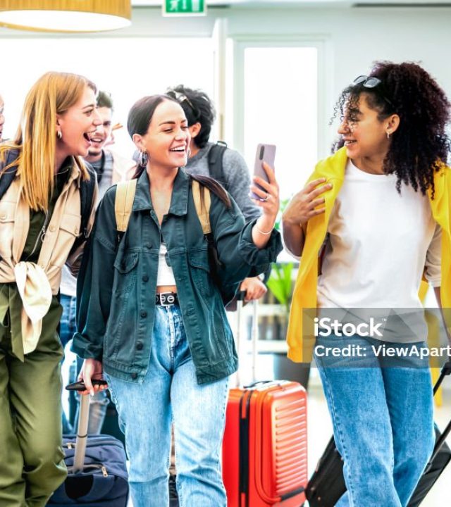 Multi racial diverse friends group arriving at hotel resort lobby with suitcases - Travel vacation life style concept with young people having fun before checkin time - Bright vivid backlight filter